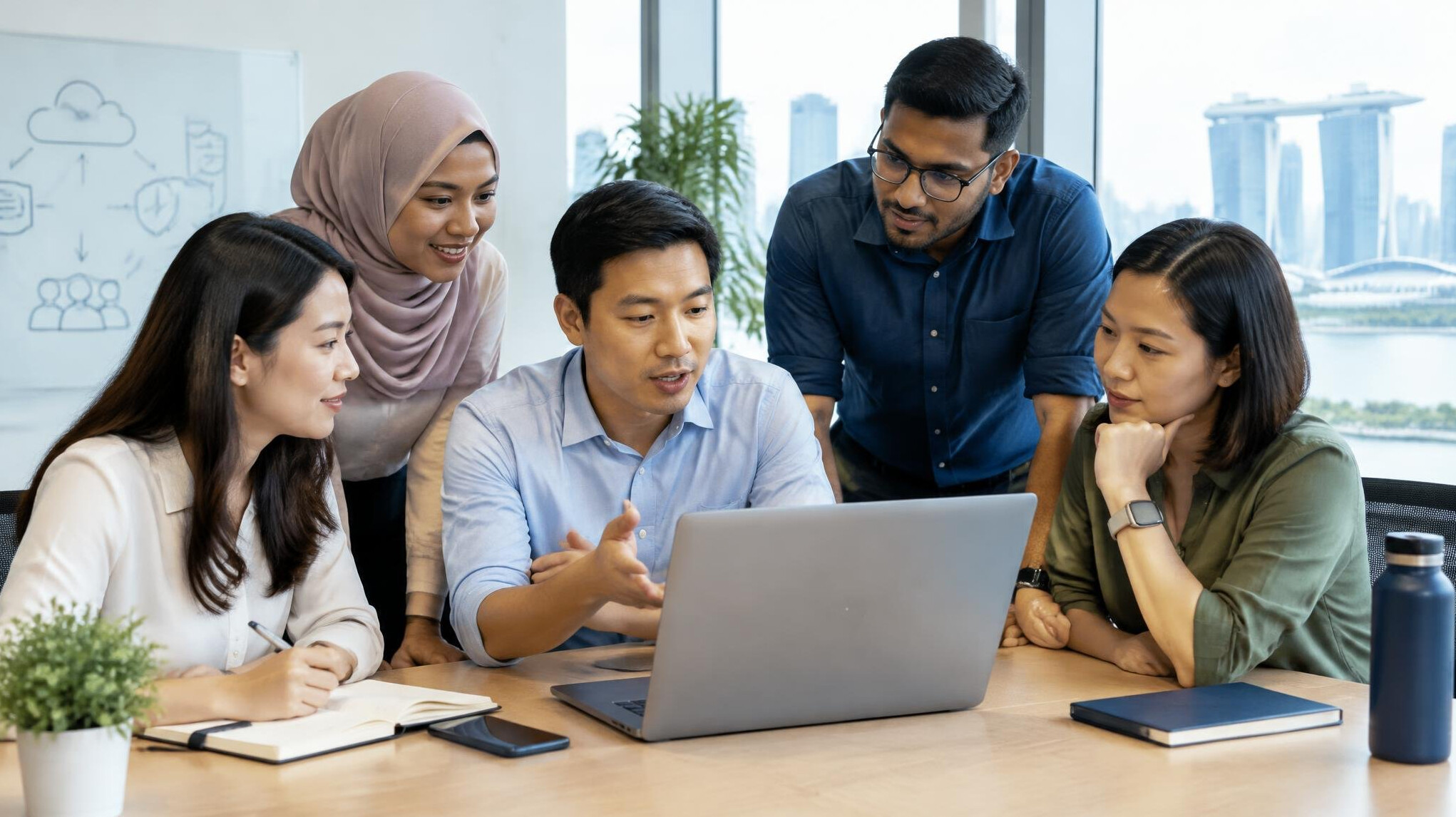 Diverse team of insurance professionals discussing software requirements around a laptop